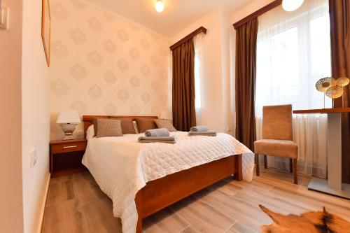 a bedroom with a bed and a chair and a window at Prenoćište Dvorište in Novi Sad