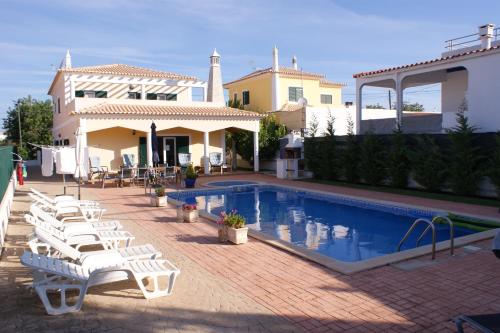 a swimming pool with white lounge chairs next to a house at Vivenda Luz e Lúdica in Altura