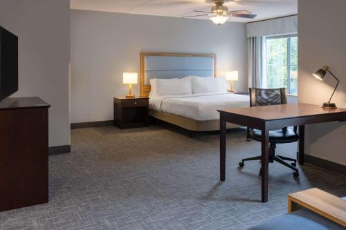 Habitación de hotel con cama, escritorio y mesa. en Homewood Suites by Hilton Rochester/Greece, NY, en Rochester