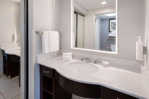 La salle de bains blanche est pourvue d'un lavabo et d'un miroir. dans l'établissement Homewood Suites by Hilton Rochester/Greece, NY, à Rochester