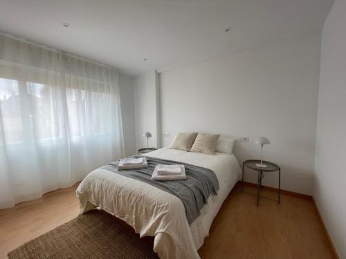 biała sypialnia z łóżkiem i oknem w obiekcie Alojamiento céntrico en Cangas w mieście Cangas de Morrazo
