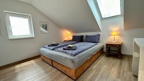 um quarto com uma cama com almofadas azuis e 2 janelas em Třeboňský penzion em Třeboň