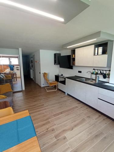 a kitchen with white cabinets and a wooden floor at Bilocale Funivie in Breuil-Cervinia