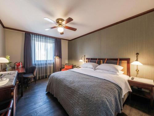 a bedroom with a bed and a ceiling fan at Mercure Hotel Frankfurt Airport Langen in Langen