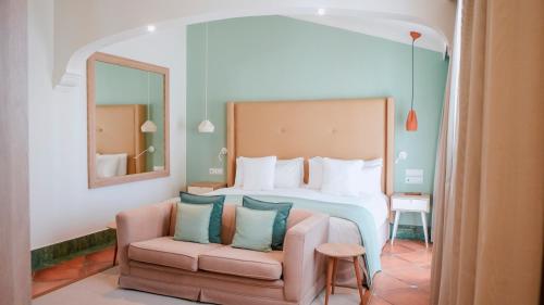 a bedroom with a bed and a chair and a mirror at Palacio de Sancti Petri, a Gran Meliá - The Leading Hotels of the World in Chiclana de la Frontera