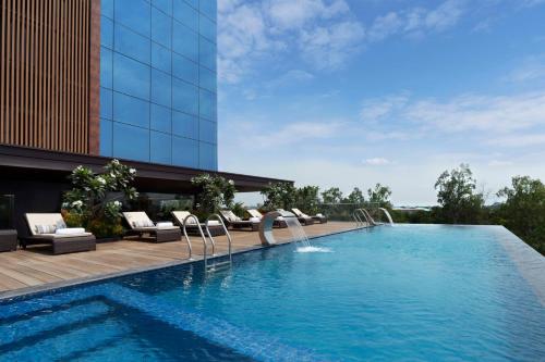 a swimming pool with chairs and a building at Hyatt Place Bharuch in Bharuch
