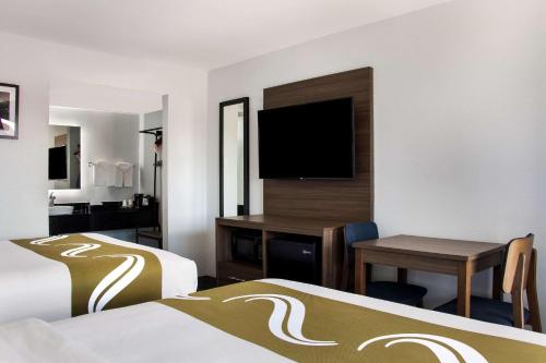 a hotel room with two beds and a desk with a television at Quality Inn Santa Fe New Mexico in Santa Fe