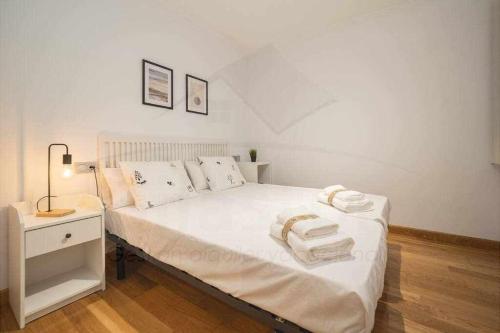 una camera da letto con un letto bianco e asciugamani di San Miguel Playa a Gijón