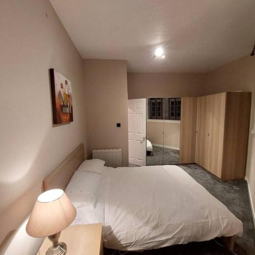 a bedroom with a white bed and a desk with a lamp at Crossways Cottage Quirky 2 bedroom cottage in Damdale, Central Peebles in Peebles