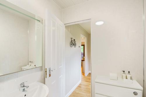 Baño blanco con lavabo y espejo en Conifer Lodge 25 with Hot Tub, en Newton Stewart