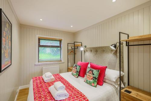 1 dormitorio con 1 cama grande con almohadas rojas en Conifer Lodge 25 with Hot Tub, en Newton Stewart