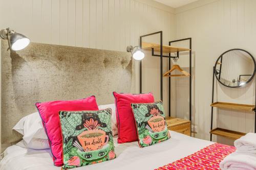 a bedroom with a bed with pink and green pillows at Conifer Lodge 25 with Hot Tub in Newton Stewart