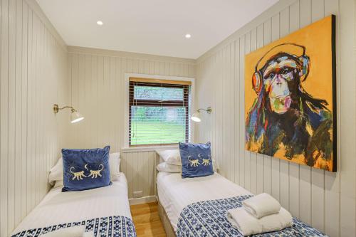 two beds in a room with a painting on the wall at Conifer Lodge 25 with Hot Tub in Newton Stewart