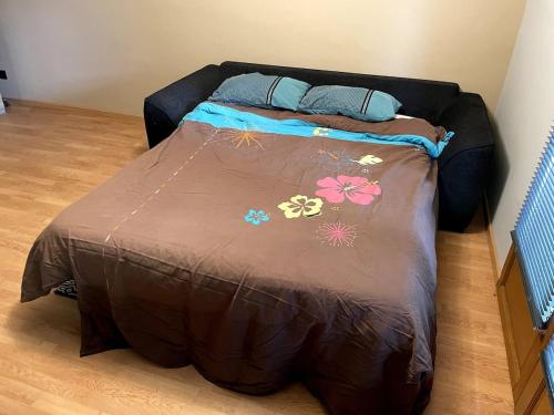 a bed with a brown comforter with flowers on it at Jolie studio toutes saisons, impossible de communiquer merci de passer sur autre site pour le moment in Crots