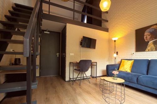 a living room with a blue couch and a staircase at Bosrijk Ruighenrode in Lochem