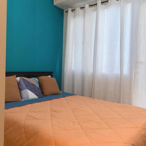 a bedroom with a bed with blue walls and white curtains at Condo Unit 2 min away from Southmall, Las Pinas in Manila