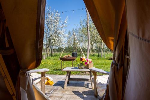 uma mesa numa tenda com flores em Cabin Margot with hot tub in private garden em Kaprijke