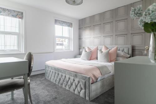 a white bedroom with a large bed with pink pillows at Harbour Heights in Folkestone