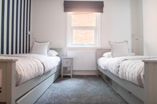 a white bedroom with two beds and a window at Harbour Heights in Folkestone