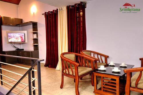a living room with a table and chairs and a television at Sriniketana Homestay in Madikeri