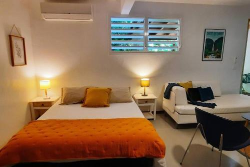 um quarto com uma cama, um sofá e uma janela em Studio à la campagne, L'Aqua verde em Le Gosier