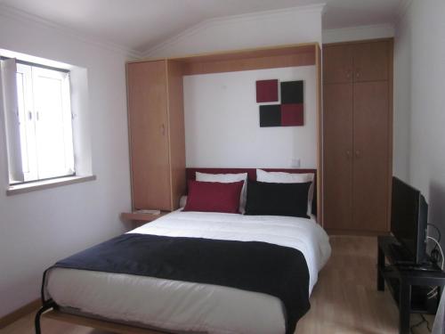 a bedroom with a large bed with red and black pillows at Casinha da Pedra in Tomar