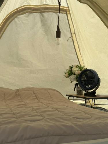 a bedroom with a tent with a fan and flowers at Moon hill camp in Kampong Egang