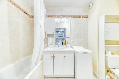 La salle de bains blanche est pourvue d'un lavabo et d'une baignoire. dans l'établissement 5min Alpexpo 4 personnes garage privé terrasse, à Grenoble