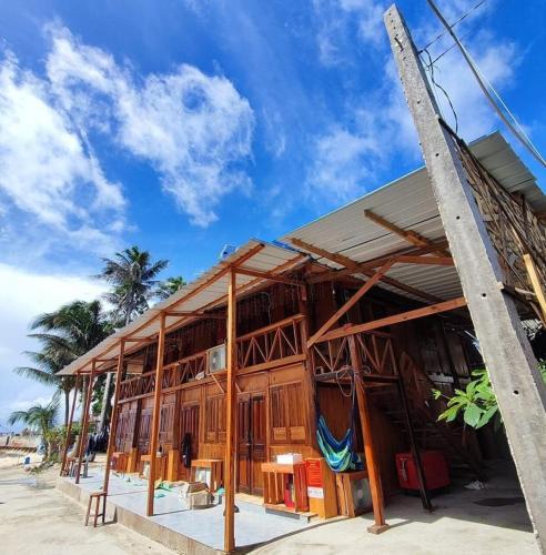 a wooden building on the beach with palm trees at Mộc Homestay Đảo Phú Quý in Cu Lao Thu