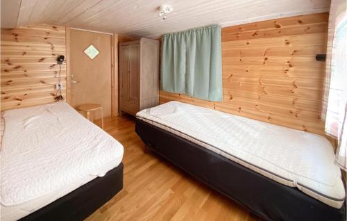 a bedroom with two beds in a wooden room at Stuga 4 in Nybro