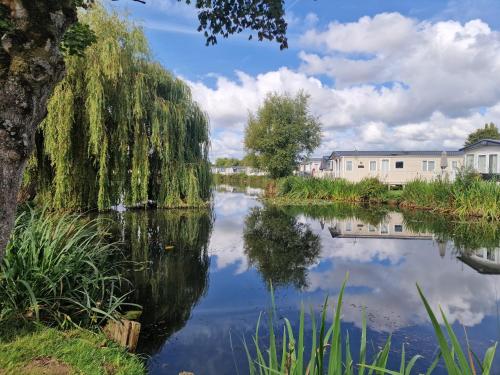 a view of a river with buildings in the background at Lakeside Cotswold Holiday Home in Cirencester