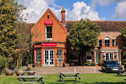 a brick building with benches in front of it at Muthu Belstead Brook Hotel in Ipswich