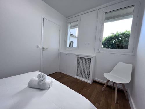 ein weißes Schlafzimmer mit einem weißen Bett und einem Stuhl in der Unterkunft 4P - 1BR - Boulogne Paris Parc des Princes in Boulogne-Billancourt
