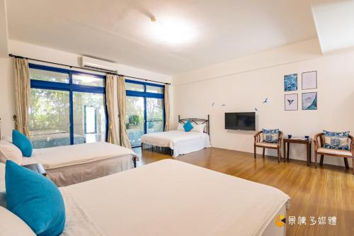 a large room with two beds and a tv at Promised Land B&B in Taitung City