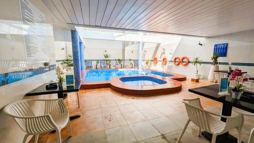 una piscina en una habitación con mesa y sillas en City Tower Hotel, en Fujairah