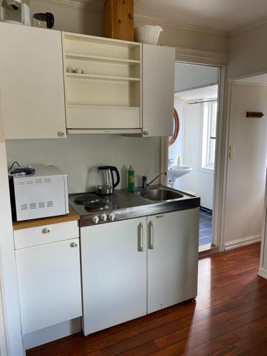 a kitchen with white cabinets and a sink at Rosendal Apartments Motellet in Rosendal