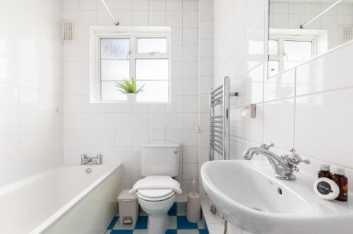 ein Badezimmer mit einer Badewanne, einem WC und einem Waschbecken in der Unterkunft The Chiswick Collection in London