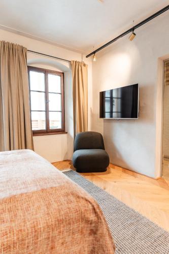 a bedroom with a bed and a chair and a flat screen tv at H5 Grauer Bär Studios & More in Innsbruck