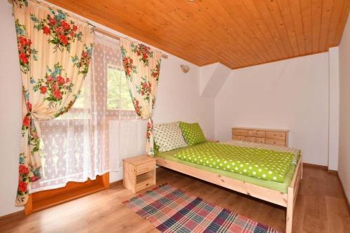 a bedroom with a green bed and a window at Chata Erika in Pusté Pole