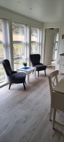 a living room with chairs and a table and windows at Rosendal Apartments Motellet in Rosendal
