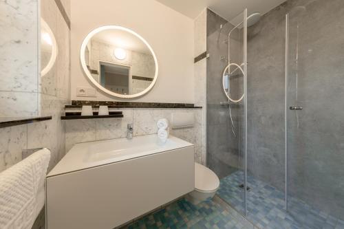 ein weißes Bad mit einem Waschbecken und einer Dusche in der Unterkunft Residenz Südwesthörn in Norderney
