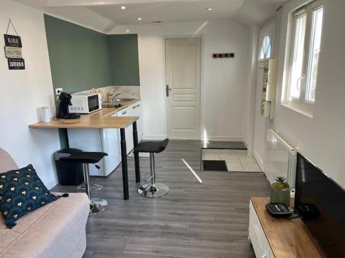 a living room with a couch and a kitchen with a counter at Petite maisonnette proche de Giverny in Bonnières-sur-Seine