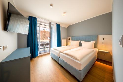 1 dormitorio con cama y ventana grande en Residenz Südwesthörn, en Norderney