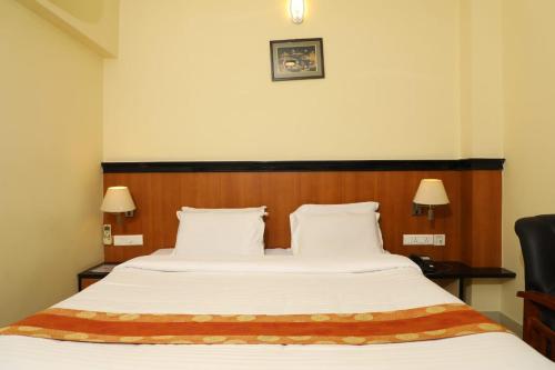 Schlafzimmer mit einem großen Bett mit einem Kopfteil aus Holz in der Unterkunft Hotel Shrie Shaanth in Salem