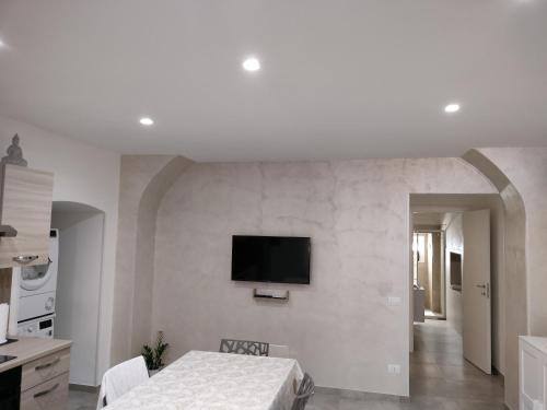 Dieses weiße Zimmer verfügt über ein Bett und einen TV an der Wand. in der Unterkunft MIA GUEST ROOM in Triggiano