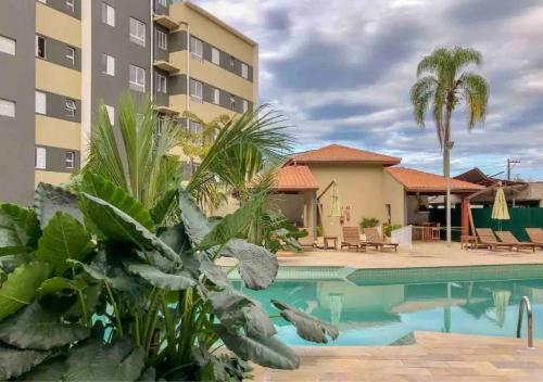 une piscine dans un hôtel avec des palmiers et un bâtiment dans l'établissement JARDIM DAS PALMEIRAS II - HOME RESORT, à Ubatuba