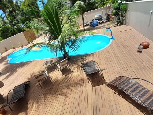 a pool with chairs and a palm tree on a deck at Casa Sol do Gostoso in São Miguel do Gostoso