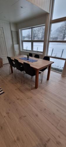 a wooden table with chairs in a room with windows at Rosendal Apartments Motellet in Rosendal