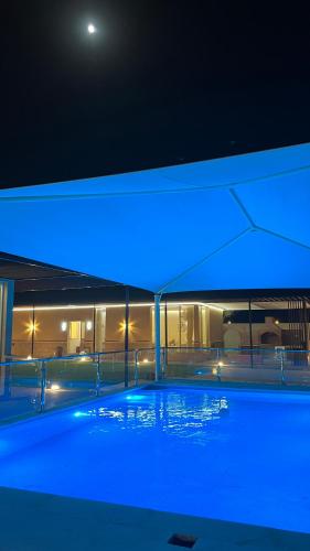 Marbella Resort في العين: مسبح في الليل مع اضاءة زرقاء