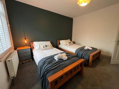 a bedroom with two beds and a lamp and a window at The Limes - Stylish City Centre Retreat in Peterborough